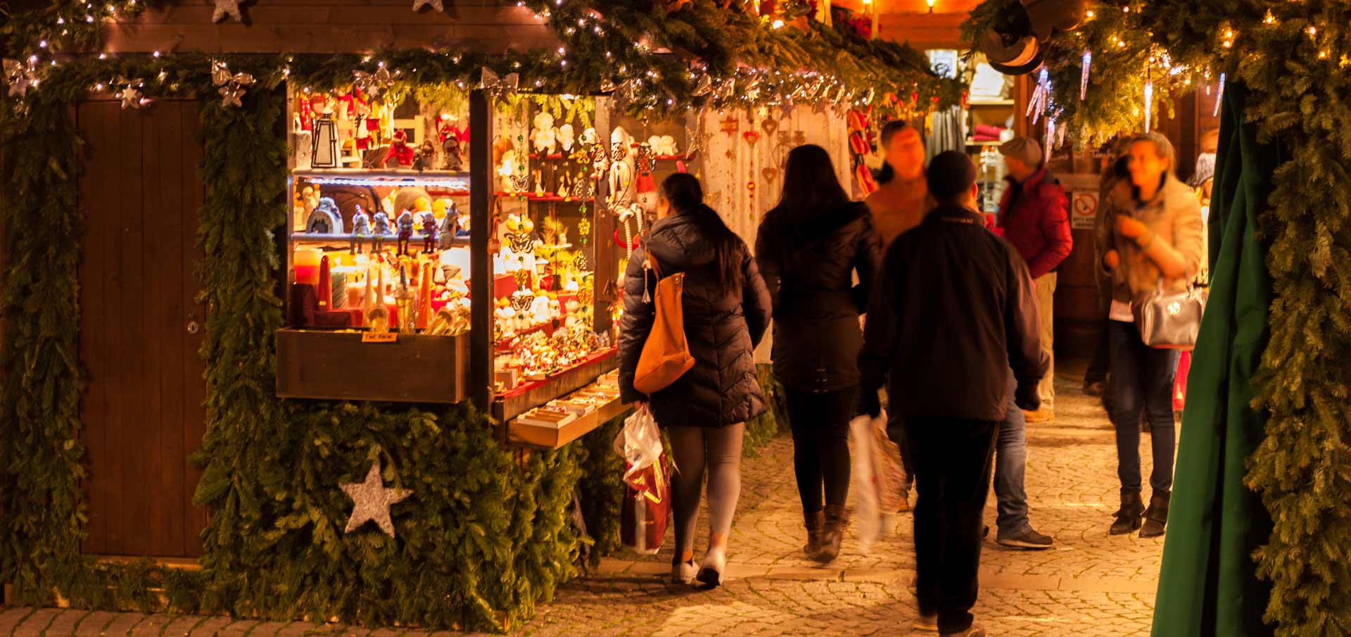 Christmas market with people browsing stalls of gifts and decorations